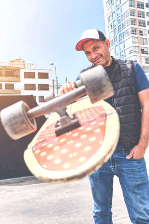 The perfect way to get through these streets, teenager in street clothes stands with a longboard, looks at the camera and smiles. Street culture.の写真素材