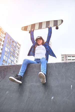 Girl having fun riding skateboards at skate park, Portrait of smiling young female skateboarder holding her skateboard. Recreational Activity Concept.の写真素材
