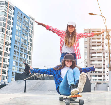 Attractive female friends having fun riding skateboards at the skate park, Smiling portrait of young skateboarders holding her skateboard.の写真素材