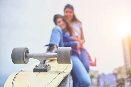 Attractive female friends having fun riding skateboards at the skate park. Selective focusの写真素材