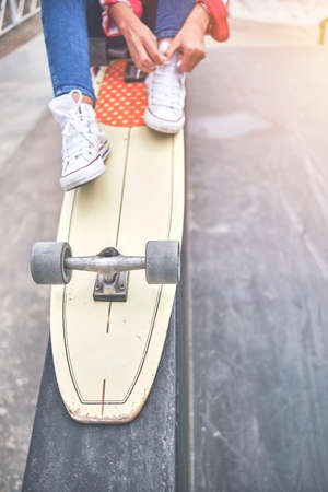 Skater girl getting ready for action, tying shoestring. First step. Selective focus