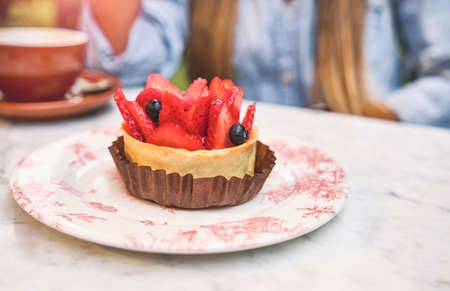 Young woman tasting strawberry-topped cake, Selective focus.の写真素材
