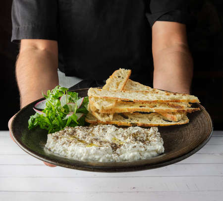 Italian cheese stracciatella -buffalo mozzarella- on a black plate served with fresh arugula and toasted bread. Chefs presentation.の写真素材