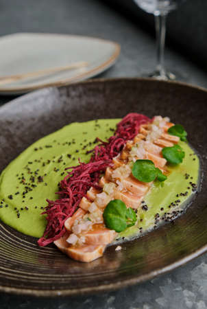 Close-up of savory Japanese salmon tataki dish topped with sesame and served with crispy strips. isolated on modern background. selective focusの写真素材