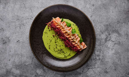 Close-up of savory Japanese salmon tataki dish topped with sesame and served with crispy strips. isolated on modern background. selective focusの写真素材