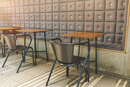Coffee shop interior with upholstered and concrete wall, metal chairs and wooden tables. Selective Focus.の写真素材