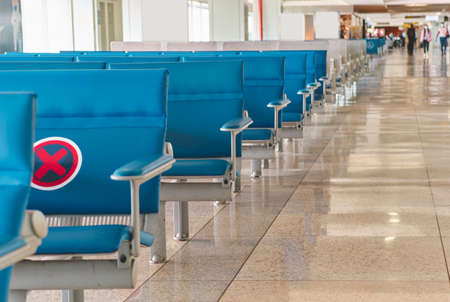 Empty chairs in the departure hall at airport, blurred plane on a background.の写真素材