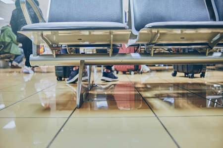 Empty chairs in the departure hall at airport, blurred plane on a background.
