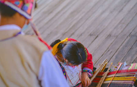 Indigenous woman showing traditional weaving technique and textile making in the Andes mountain range of South America in Peru, Selective focus.の写真素材