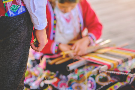 Indigenous woman showing traditional weaving technique and textile making in the Andes mountain range of South America in Peru, Selective focus.の写真素材