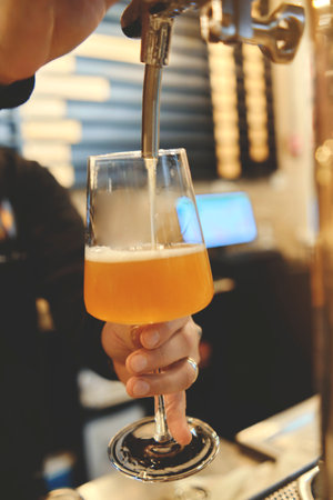 Hand of bartender pouring a large lager beer in tap. Pouring beer for client. Selective focus. Weekend timeの写真素材