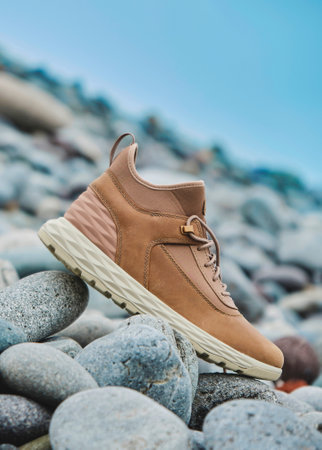 A pair of brown leather waterproof trekking boots on a sea coast. Hiking concept.の写真素材