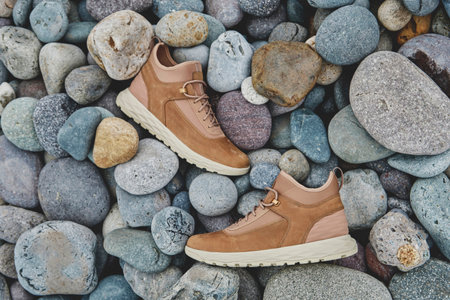 A pair of brown leather waterproof trekking boots on a sea coast. Hiking concept.の写真素材