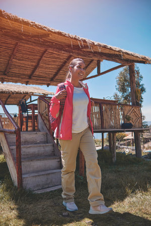 Young tourist comes out of a wooden cabin with a view of the mountain. hiking conceptの写真素材