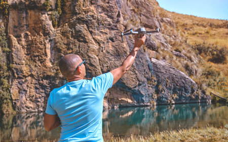 Young man with modern drone in mountains, back viewの写真素材