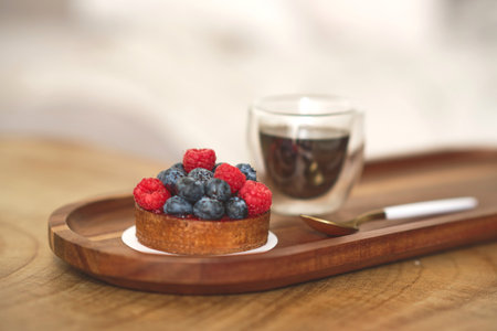 Enjoy this delicious dessert cupcake with raspberries and coffee cup in pastry cafe.Tasty fresh cake with berries and espresso on wooden tableの写真素材