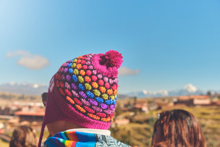 Back view of young traveler in hat standing over mountain peaks. Autumn traveling scene, wanderlust concept.の写真素材