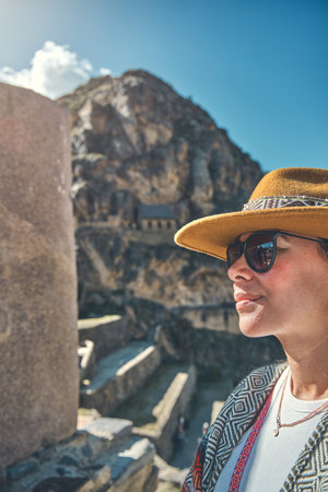 Traveler hipster girl in hat with backpack exploring ruins of Ollantaytambo Ruins in Sacred Valley of Peruの写真素材