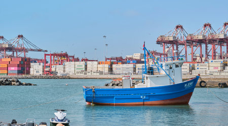 Callao, Peru - january 4 2024. Small fishing boat near dock and containers in the port of Callao.のeditorial素材