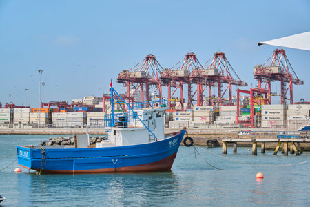 Callao, Peru - january 4 2024. Small fishing boat near dock and containers in the port of Callao.のeditorial素材