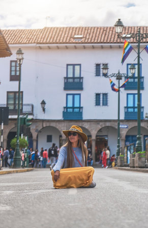 Young traveler woman with brown hat sitting on the street in the center of Cusco, Peru.