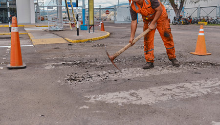 Three men in orange work clothes are painting a crosswalkの写真素材