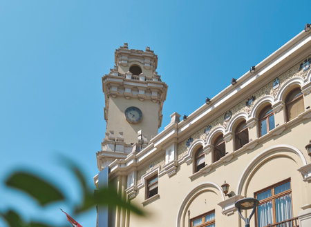 A tall building with a clock tower and a balcony. The building is white and has a lot of windowsの写真素材