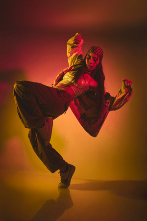 A woman is dancing in a room with a yellow background. Urban dancer concept.