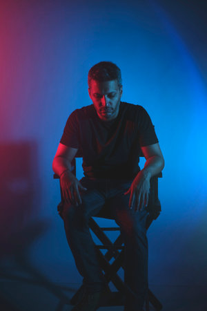 A man is sitting in a chair with his hands on his knees