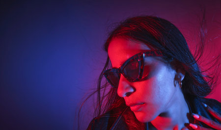 A woman with long hair and sunglasses is standing in front of a blue backgroundの写真素材