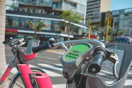 Two bikes are parked next to each other on a city street. One of the bikes has a green screen on it