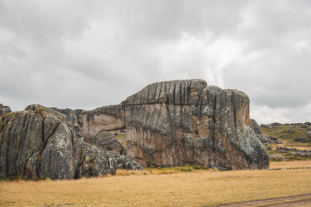 A large rock formation with a small hole in the middle, traveling through the peruvian andesの写真素材