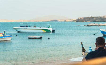 A man is sitting on a beach with a bottle of waterの写真素材