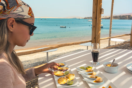 A woman is sitting at a table with a plate of food in front of herの写真素材