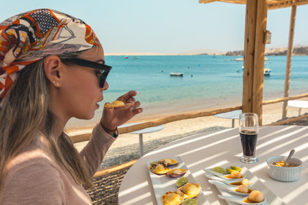 A woman is eating food at a beachの写真素材