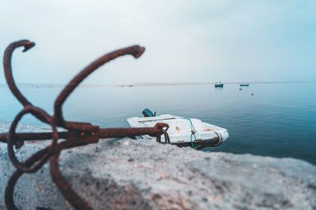 A boat is sitting on the water next to a rusty anchorの写真素材