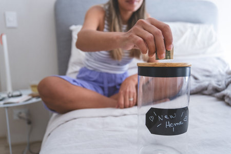 A woman is putting money into a jar labeled New Home. New home concept.
