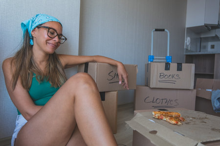 A woman is sitting on the floor with boxes labeled clothes. New home concept.の写真素材