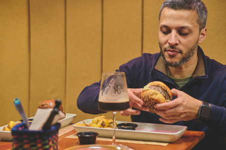 Young man enjoying a tasty burger in craft beer barの写真素材