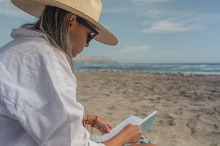 Young woman reading a book on the beach during summer vacationの写真素材