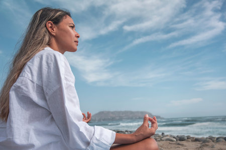 Young woman meditating on beach yoga mat during summer vacationの写真素材