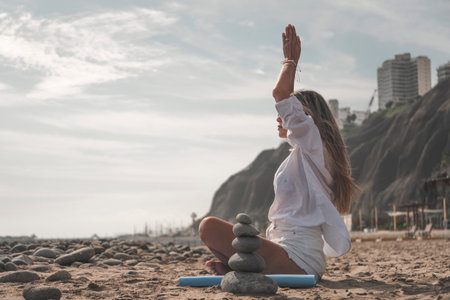 Young woman meditating on a rocky beach during summertimeの写真素材