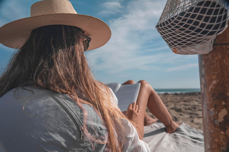 Woman relaxing on beach reading book enjoying summer meditation timeの写真素材