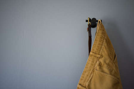 pair of pants and a belt hanging on a blue wallの写真素材
