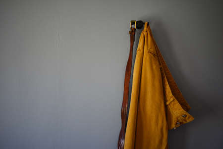 pair of pants and a belt hanging on a blue wallの写真素材