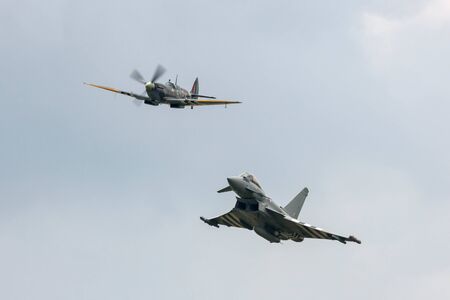 RAF Waddington, Lincolnshire, UK - July 6, 2014: Supermarine Spitfire from the Royal Air Force (RAF) Battle of Britain Memorial Flight (BBMF) leads a RAF Eurofighter Typhoon FGR4 fighter aircraft in formation.のeditorial素材