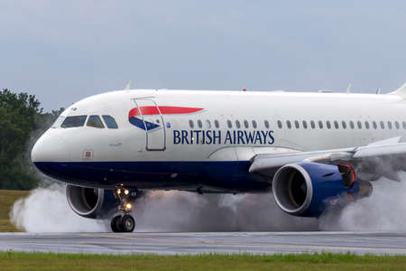 Farnborough, UK - July 19, 2014: British Airways Airbus A318-112 aircraft G-EUNB landing on the wet runway with reverse thrust spraying water.のeditorial素材