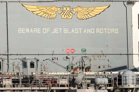Melbourne, Australia - August 30, 2017: Beware of jet blast and rotors sign on the deck of the USS...