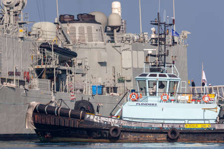 Melbourne, Australia - June 12, 2015: Tug boat PB Flinders assigning the HMAS Melbourne (FFG 05) guided-missile frigate of the Royal Australian Navy dock at Station Pier in Melbourne.のeditorial素材