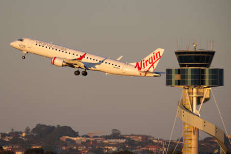 Sydney, Australia - October 9, 2013: Virgin Australia Airlines Embraer E-190 twin engine regional jet airliner landing at Sydney Airport with the air traffic control tower in the background.のeditorial素材